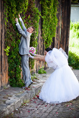 young groom running away from bride and climbing on high wall