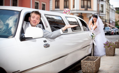 Handsome groom sitting in car while bride pushing it