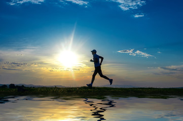 Silhouette man running on meadow over river