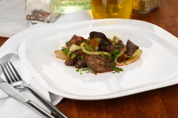 Fried chicken livers on plate on wooden table close-up