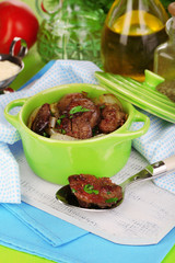 Fried chicken livers in pan on wooden table close-up