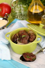 Fried chicken livers in pan on wooden table close-up