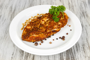 Roasted chicken fillets on white plate, on wooden background