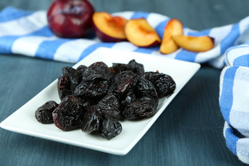 Fresh and dried plums  on napkin, on wooden background
