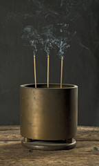 Antique incense burner on wooden table in dark background (Still