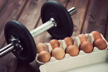 Fototapeta premium Bodybuilding symbols: dumbbell and protein food, horizontal shot