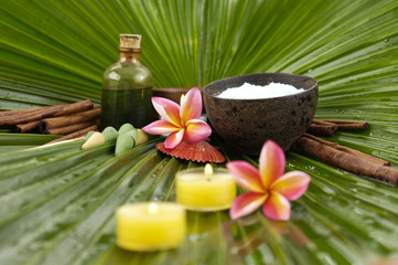 spa oil , salt in bowl , frangipani ,candle on palm leaf