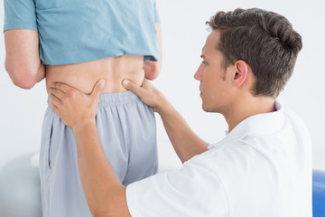 Obraz premium Hands massaging mans lower back in gym hospital