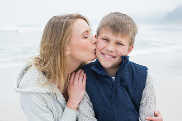 Mother kissing boy at beach