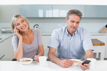 Couple with cellphones while having breakfast