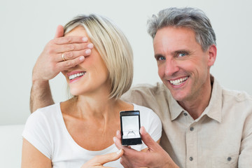 Man covering woman's eyes to offer her an engagement ring