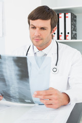 Fototapeta premium Concentrated male doctor looking at x-ray picture of spine