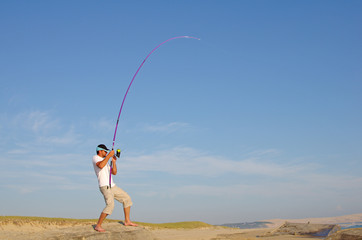 pêcheur en surf casting combattant un poisson