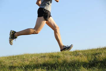 Side view of a jogger legs running on the grass