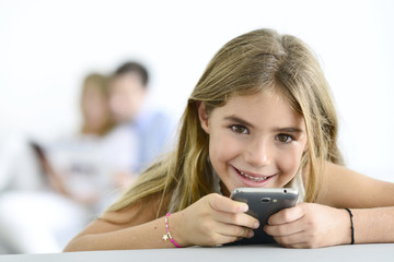 Smiling little girl playing with smartphone
