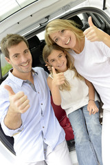 Cheerful family in car trunk showing thumbs up