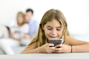 Smiling little girl playing with smartphone