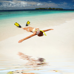 Cute woman with snorkeling equipment relaxing on the tropical be