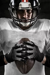 Foto op Canvas Portrait of american football player holding a ball and looking © guerrieroale