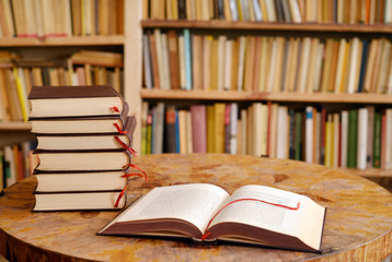 A place for study the books on a table with pile of books and a bookshelf in the background