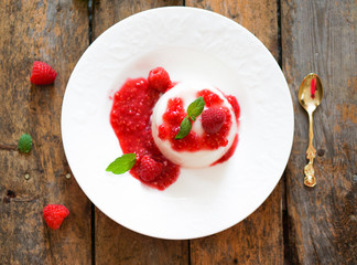 Delicious italian dessert panna cotta with raspberry sauce and m