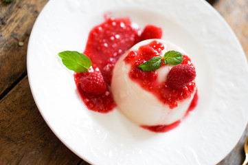 Delicious italian dessert panna cotta with raspberry sauce and m