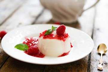 Delicious italian dessert panna cotta with raspberry sauce and m