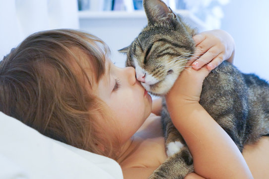 Child is kissing a cat