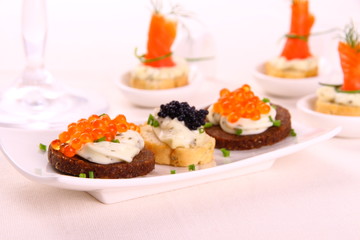 Red and black caviar on bread chunks as snack