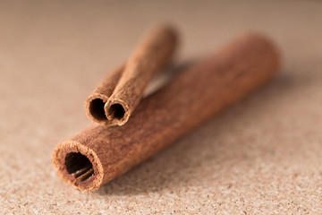Two cinnamon sticks on corkwood background.