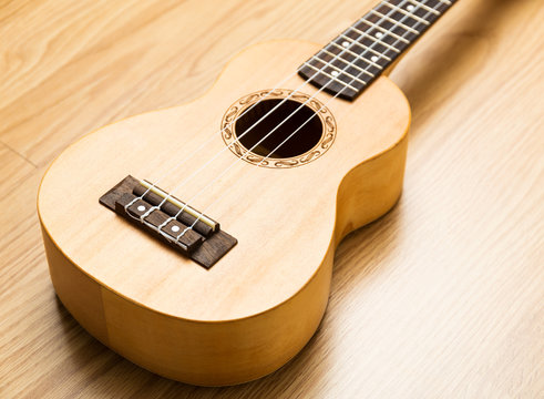 Ukulele over the wooden background