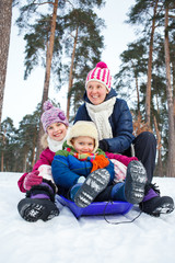 Fototapeta na wymiar Funny family is sledging in winter-landscape