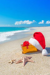 Santa Claus hat and christmas gift box on the seashore with sea