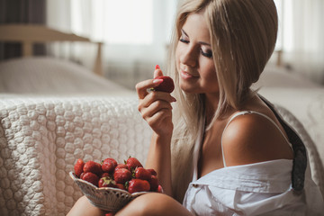 Young woman laying on bed with strawberry