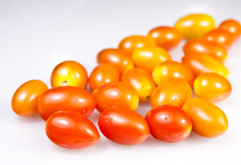 a pile of baby plum tomatoes on a white background