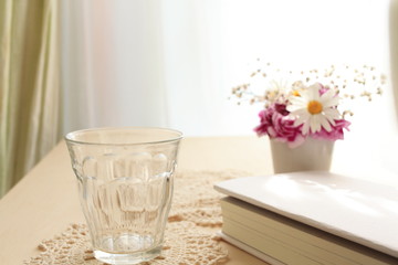 Empty glass on table with book and flower