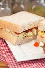 Fresh egg and tomato on white sandwich in rustic kitchen setting