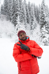 Fototapeta na wymiar African American Cheerful black man in ski suit in snowy winter