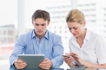 Obraz premium Businessman and woman using digital tablet and cellphone at offi