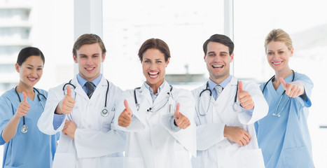 Fototapeta na wymiar Cheerful doctors gesturing thumbs up at hospital