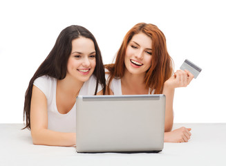 two smiling teenagers with laptop and credit card