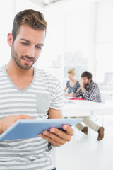 Obraz premium Man using digital tablet with colleagues in background