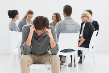 Therapy in session sitting in circle while man in foreground
