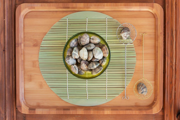 Clams in a bowl on a bamboo tray