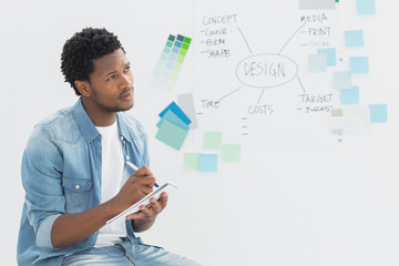 Thoughtful artist writing notes in front of whiteboard