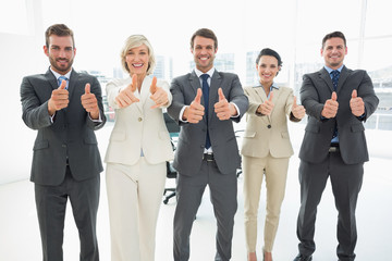 Fototapeta na wymiar Confident business team gesturing thumbs up