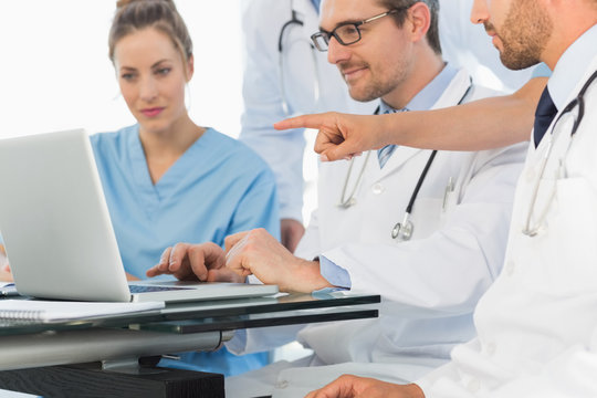Group of concentrated doctors using laptop together