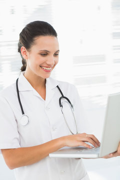 Concentrated smiling female doctor using laptop