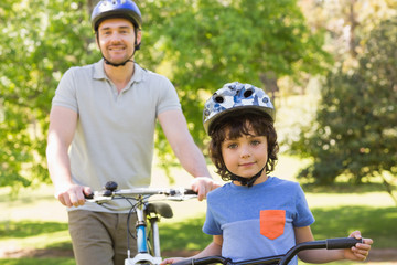 Naklejka premium Smiling man with his son riding bicycles