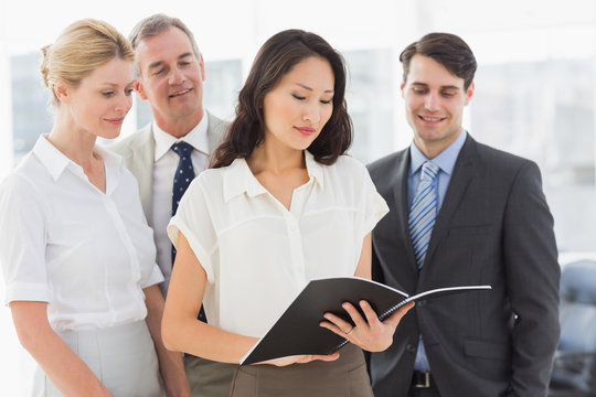 Businesswoman reading a document with her team